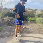 Mikey Williams Wears A Burberry Cash Hoodie Over A Father Forgive Me In Flames Black T-Shirt, El Capitan Cartel Graphic Blue Shorts, And Puma RS-X3 Court Crush Sneakers