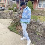 Football Player And Fashion Model Nyair Graham Outfitted In A KITH Tapestry Coaches Jacket And Christian Louboutin Louis Leather High-Top Sneakers
