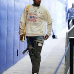 NFL Player Stefon Diggs Wears A Maison Mihara Yasuhiro x Champion Shift Side Combined T-Shirt, Blue Denim & Black Cargo Hybrid Pants And Louis Vuitton × Nike Air Force 1 Low White Red Sneakers