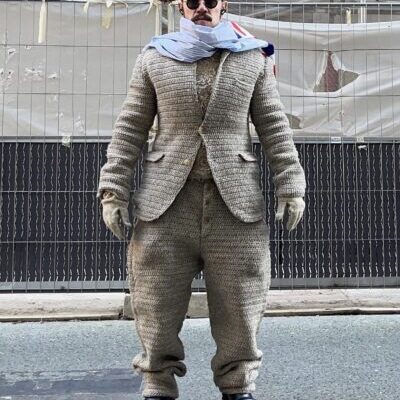 Person wearing oversized knitted suit, scarf, sunglasses