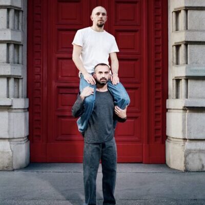 Man carrying man on shoulders before red door