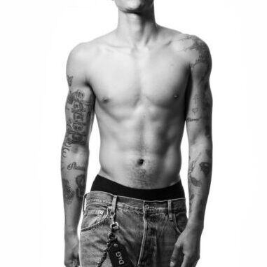 Shirtless tattooed man standing in jeans