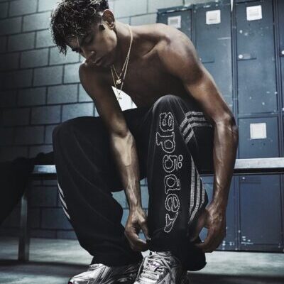 Shirtless athlete tying sneaker in locker room