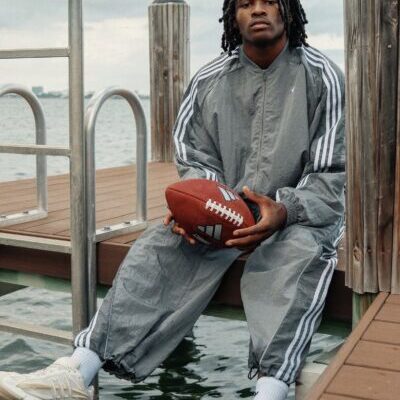 Person in tracksuit holding football on dock